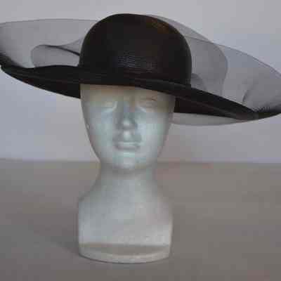 Straw wide brimmed hat with netting around brim and rhinestone pin