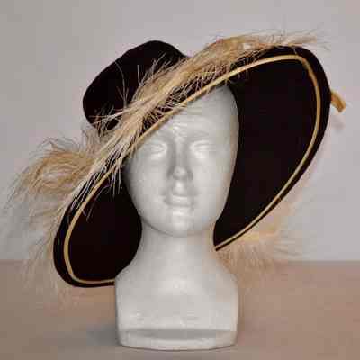 Wool felt hat with wide rigid brim, feather trim around brim and cream satin ribbon trim