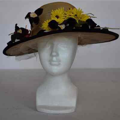 Wide brim straw hat with velvet trim on brim edge and faux flowers circling crown