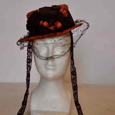 Straw boater hat with black Russian veiling on brim, black bow on crown, and lace ties