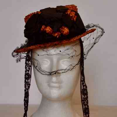 Straw boater hat with black Russian veiling on brim, black bow on crown, and lace ties