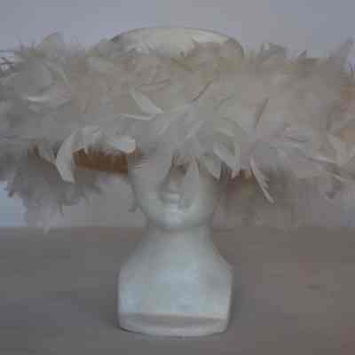 Wide brimmed hat with flat fabric covered crown , brim covered in feathers