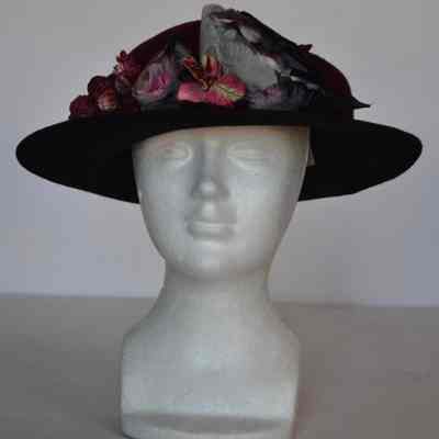 Dark red crown with black brim and cluster of faux flowers