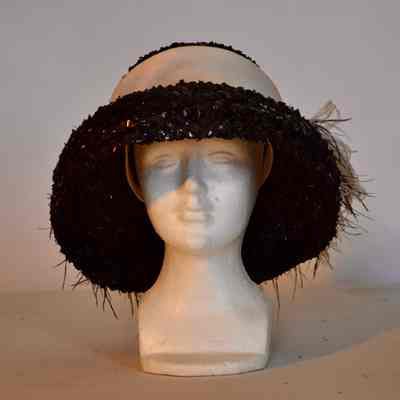 Straw mushroom hat with black and white feather accent and wide band on crown