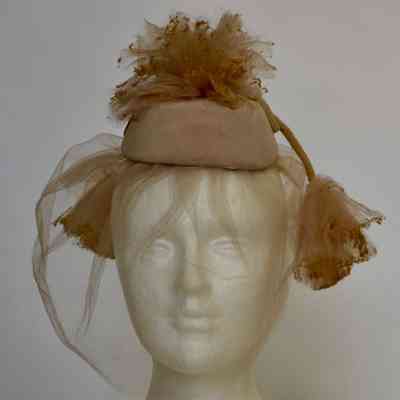 Small pillbox with net pouf on crown, front veil and pom poms attached with long velvet cords