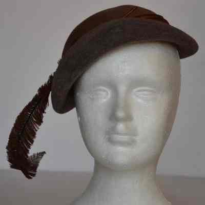Close fitting narrow brimmed with feather and pleated satin hat band