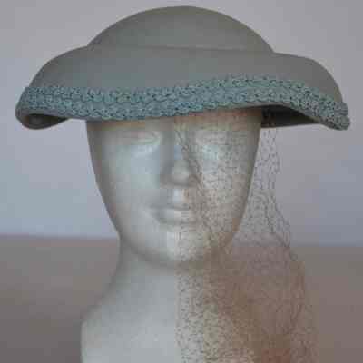 Wool felt hat with small crown and trim at edge of downturned brim and netting