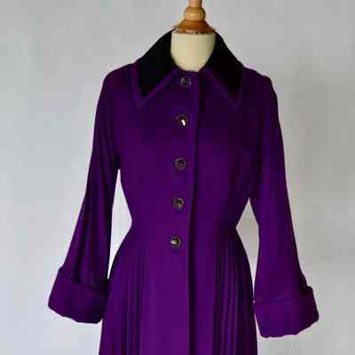 Purple wool coat with black velvet collar, fitted waist and pleated skirt and sleeves