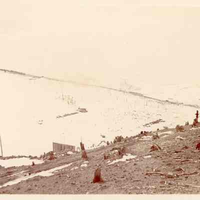 Photo 3: Foreground hillside has tree stumps. Background hillside is covered in snow. Building in lower center. Written in pencil on back: Apex, Colo. '98 & 99"