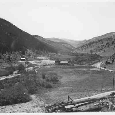 Photo 4: Creek, buildings, and road with two people walking.