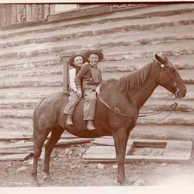 2. Don and Robert Kemp on horse at Kemp cabin, c1900. Photo by Harry H. Lake.: Two boys on a horse in front of a log cabin.