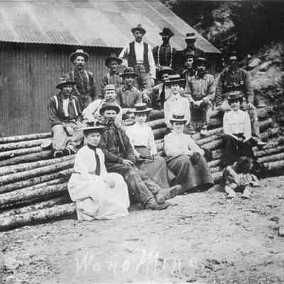 4. Wano Mine. Men and women and dog sitting on pile of logs.: digital only