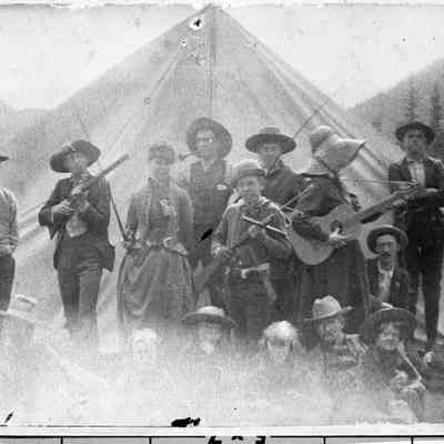 2. Camping party Eldora Valley c.1880.: In the group standing in front of a canvas tent, a man and a boy hold rifles, a woman plays guitar, a man smokes a pipe, a woman and a man hold fishing poles, and a man to the far right seems to be holding a baseball bat. Sitting are three children and four men.