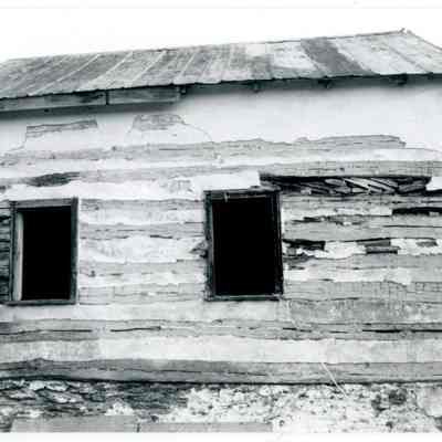 Exterior of farmhouse showing exposed wood and two windows