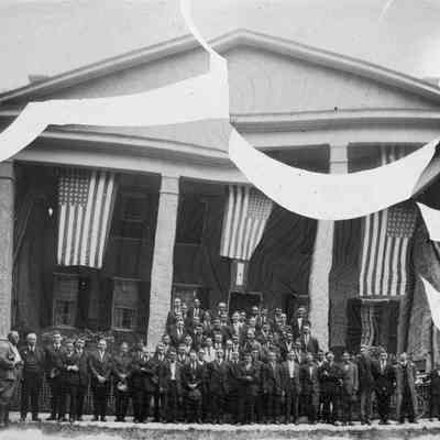 Group of men in front of a building with flags