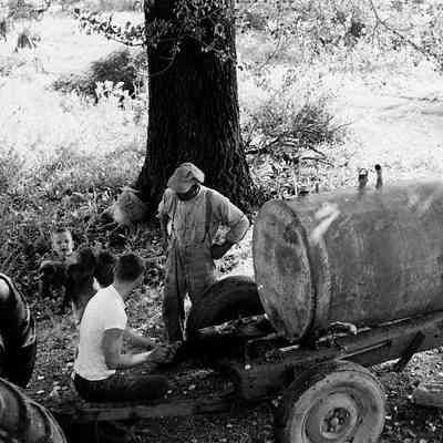 George William Myers, III. and John Monroe working on tractor at Myers farm