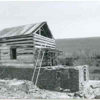 Exterior view of farmhouse with visible scaffolding and ladder