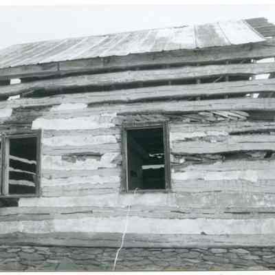 Exterior view of farmhouse with exposed wood and two windows