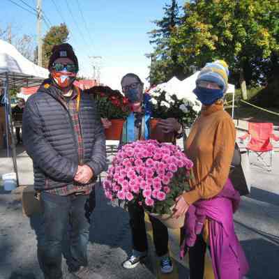 Three mask-wearing customers holding potted flowers