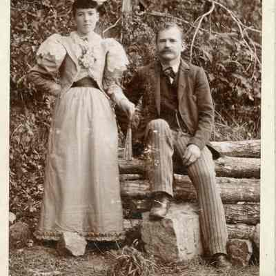 Woman standing and man sitting on a pile of logs