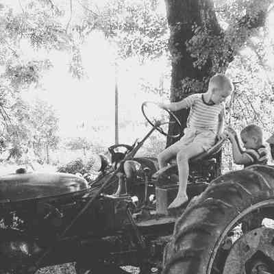 George William "Billy" Myers, III. and John Monroe working on a tractor at Myers farm