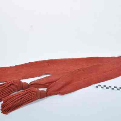 Red wool sash with fringe at both ends
