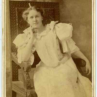White woman in white dress sitting on chair