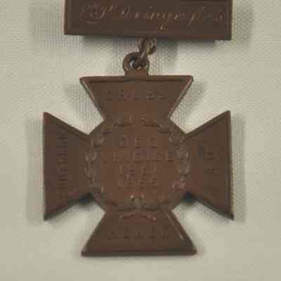 Bronze colored medal in shape of iron cross