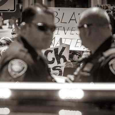 Police officers in foreground; Black Lives Matter signs in background (IMG3915003)