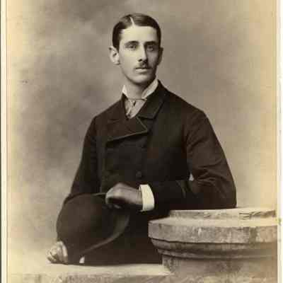 Young man standing, holding a derby hat