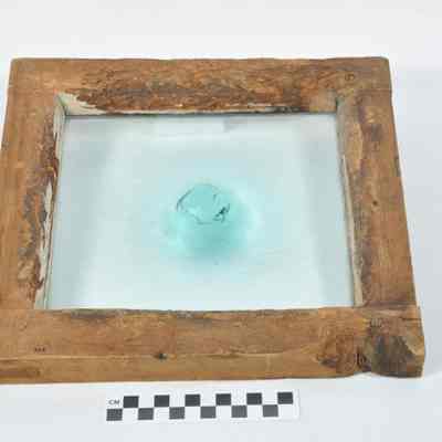 Framed piece of glass with a large pontil mark in the center