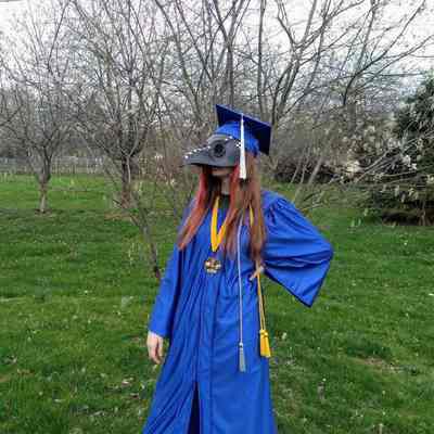 Sophia Smith in high school graduation robe with plague doctor mask