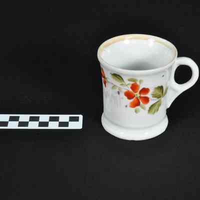 White mug with red floral design and green leaves