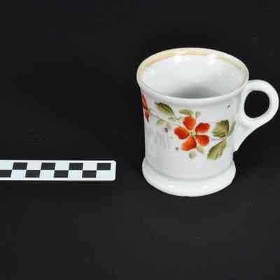 White mug with red floral design and green leaves