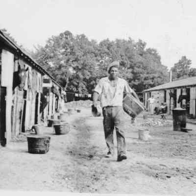 Unidentified race track stables, horses, and worker