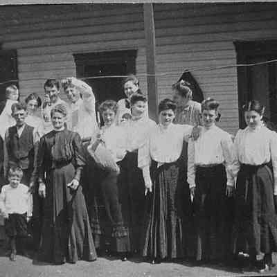 James T. and Annie Merchant with their family and unidentified young women in front of house