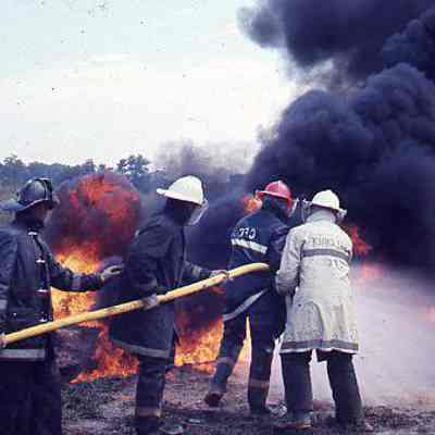 Firefighters holding hose directed at fire