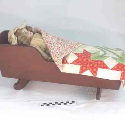German bisque doll in handmade wooden cradle with handmade quilt