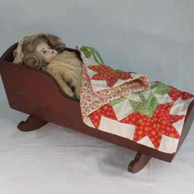 German bisque doll in handmade wooden cradle with handmade quilt