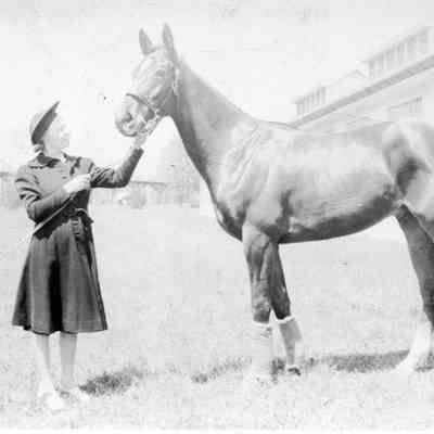 Unidentified race track stables, horse, and  woman