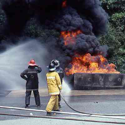 Firefighters holding hose directed at fire