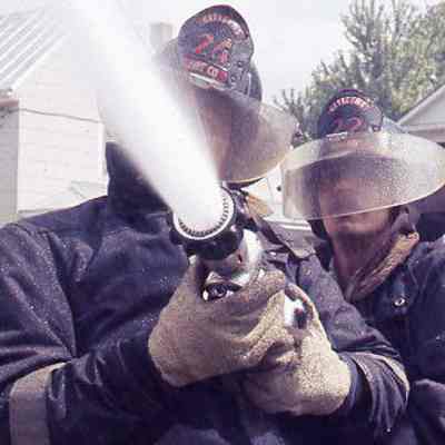 Firefighters holding hose with water spraying out