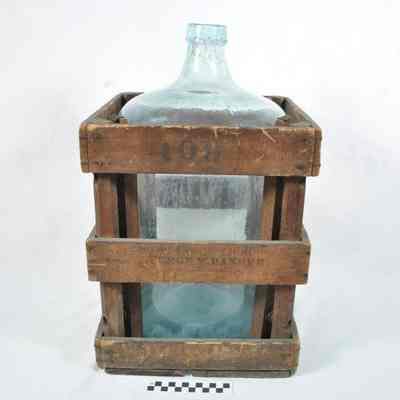 Large, light green water bottle in wooden crate