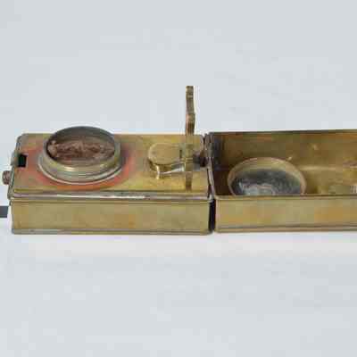 Brass box when opened has two foldable rests for a hair curling iron