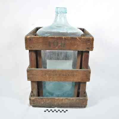 Large, light green water bottle in wooden crate