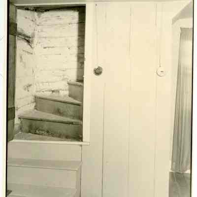 Interior stairs of farmhouse showing open doorway and wall