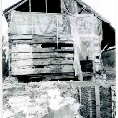 Exterior side of farmhouse showing tarps covering wood