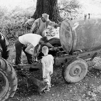 George William Myers, III. and John Monroe working on tractor at Myers farm