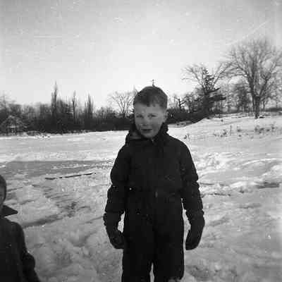 2021.12.309k: A young boy stands on snow-covered ground under a clear sky.