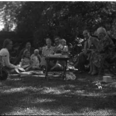 2021.12.311i: A group of people sit on the lawn having some kind of celebration.